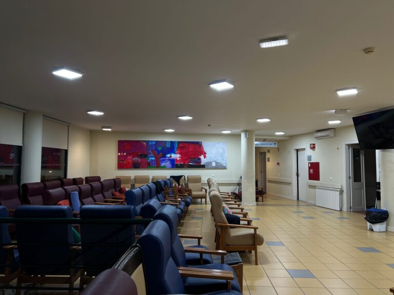 Sala de convivência iluminada com várias poltronas e um painel de arte colorido no Lar João Gonçalves Palmeiro Novo