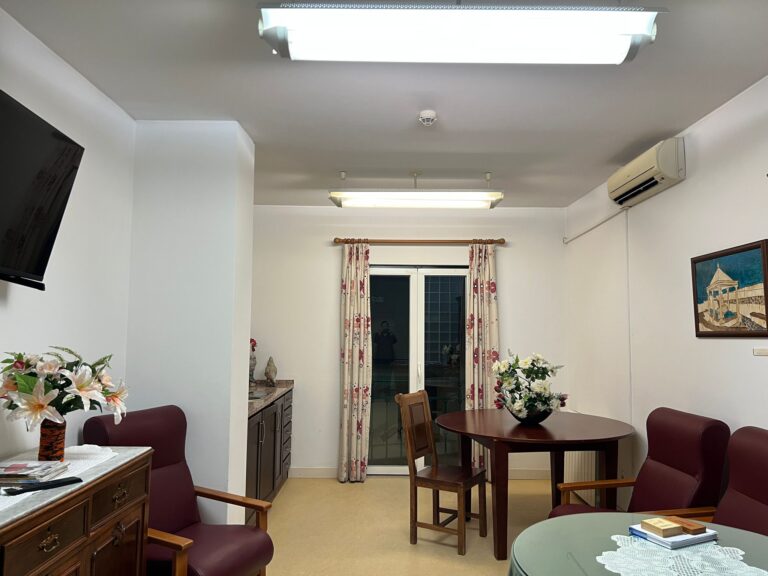 sala de visita com cadeiras, mesa com flor e decoração acolhedora no Lar João Gonçalves Palmeiro Novo